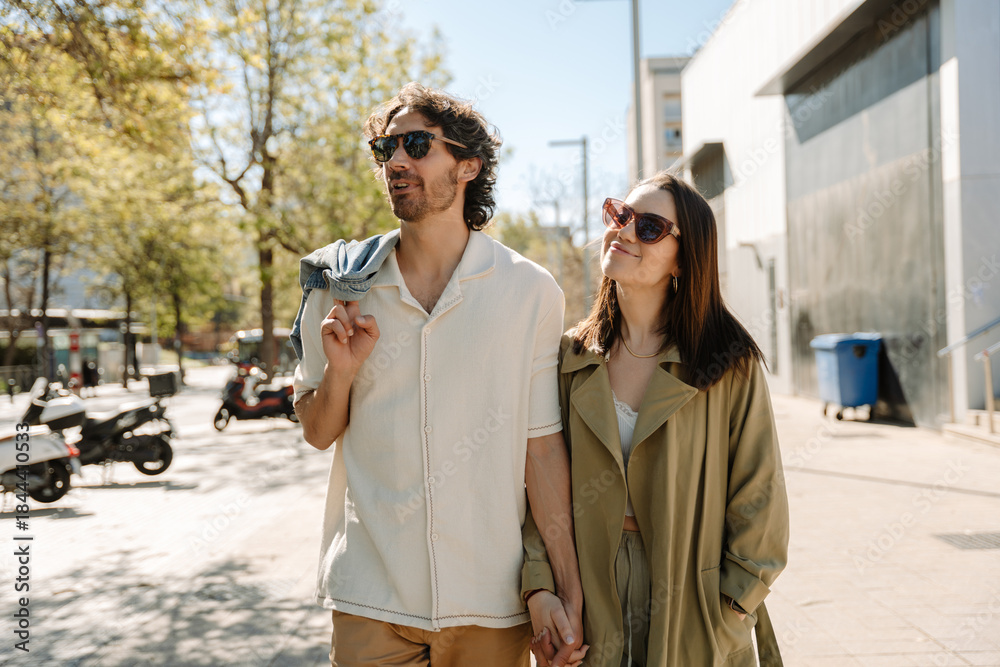Fototapeta premium A man and woman hold hands and look away while she smiles and he talks