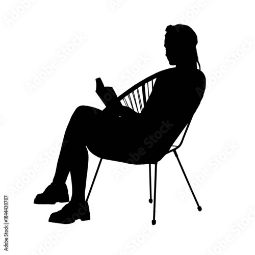 Young woman reading a book in a rattan chair outdoors.