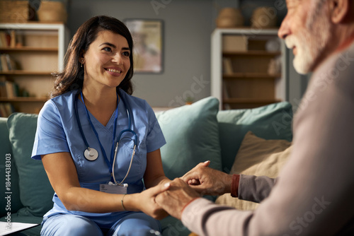 Canvas Print Female doctor holding hands with her patient during home visit.