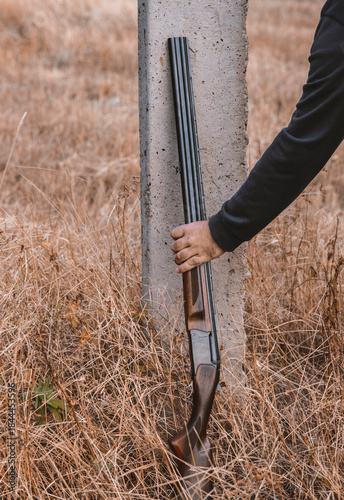 double-barreled shotgun with cartridges, leaning against a pole. Hunting concept