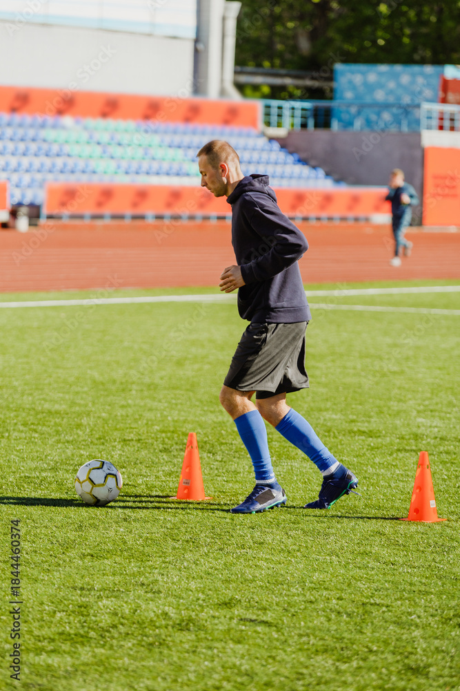 Obraz premium Male player running near cones after the ball