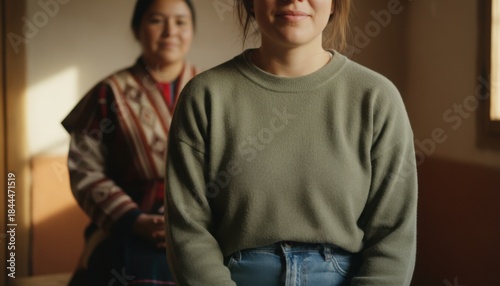 Young woman sitting calmly in front while older woman sits behind indoors representing family connection emotional support and quiet intergenerational bonding