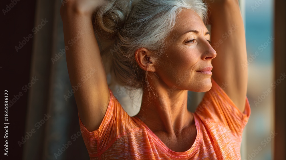 Obraz premium Woman with long gray hair is wearing an orange shirt and looking out the window. She is in a relaxed and peaceful mood