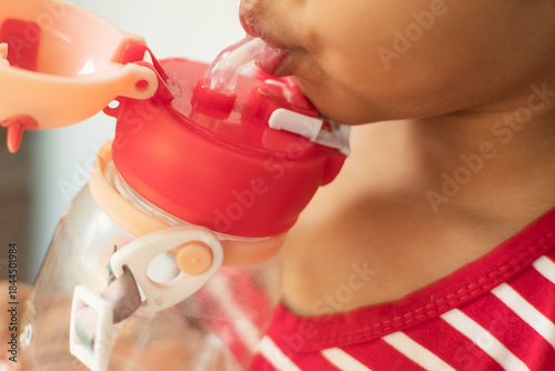 Child Drinking from a Stickered Water Bottle with Straw