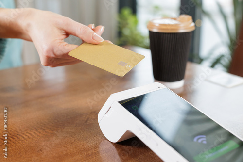 Foto Contactless NFC card payment at cafe table with POS terminal close up
