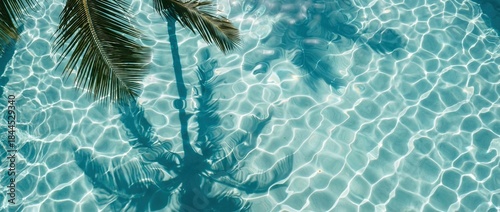 The crystal clear turquoise pool water glistens, its surface reflecting a sun-dappled oasis. The shadow of a tropical palm tree adds a touch of exotic flair.