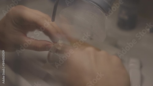 closeup hands polishing dental crown under ventilation hood, rotary handpiece refines surface and contours, technician performs