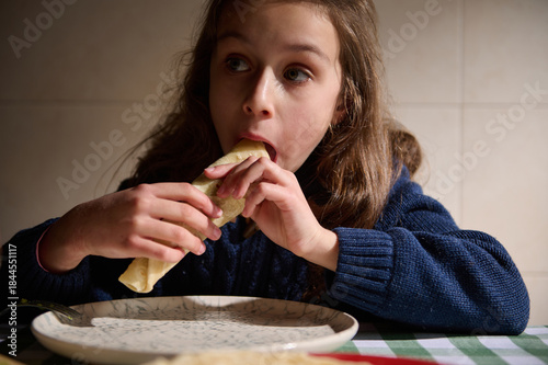 Fotografie Girl Eating A Wrap At Table In Cozy Kitchen, Casual Indoor Meal Moment