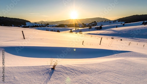 Winter landscape bathed in warm sunlight, snow-covered hills & distant mountains at sunset