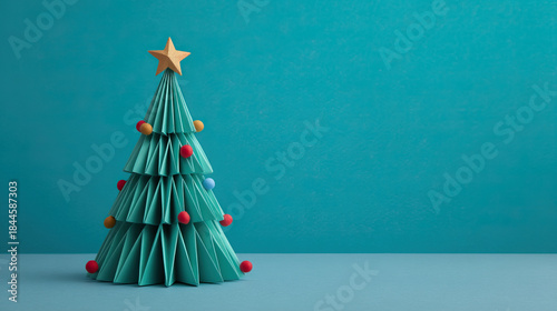 Origami christmas tree decoration paper craft with star topper and colorful ball ornament minimal turquoise background holiday celebration concept