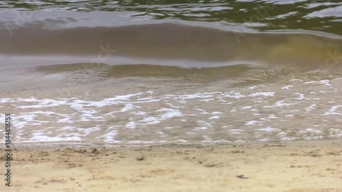 Lake shore sand and stones under the water. wave on beach, sand and water coast
