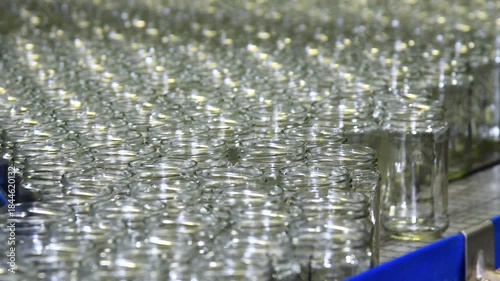 A conveyor belt with neat rows of glass jars