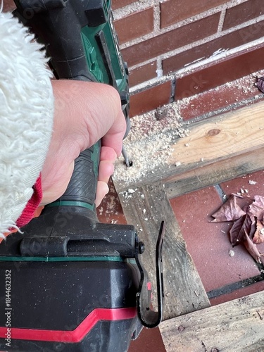 Proceso de perforación de palets de madera con broca pala para crear una base estructural. Los agujeros permiten insertar tubos de plástico invernadero, Mano sujeta taladro, vista aérea 