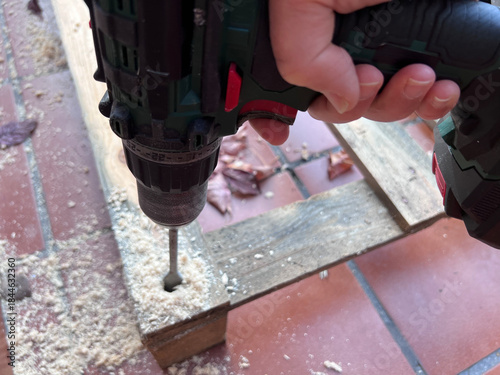 Proceso de perforación de palets de madera con broca pala para crear una base estructural. Los agujeros permiten insertar tubos de plástico invernadero, mostrando trabajo vista aérea 