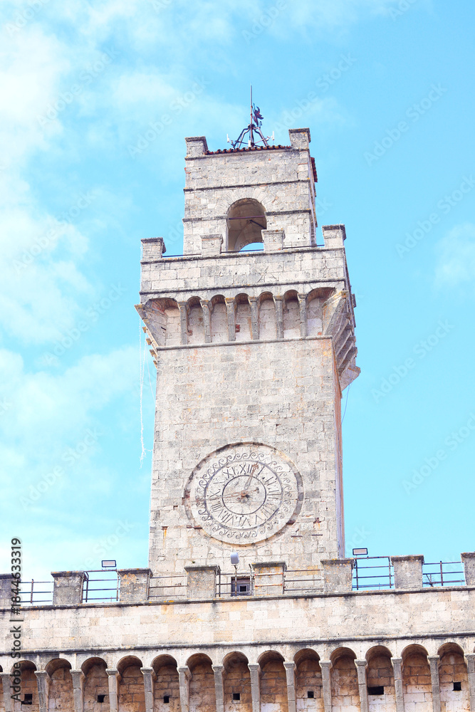 Obraz premium A close-up view of the clock tower in Montepulciano, Italy, showcasing the intricate design and architectural details against a clear blue sky.