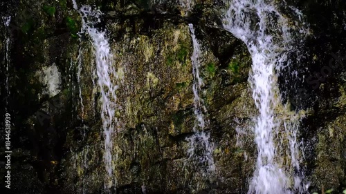 In a natural waterfall, water cascading down the rocks.