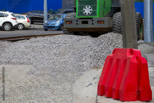 Road repair work. Red road barrier. Road equipment. Scattered gravel on the road.