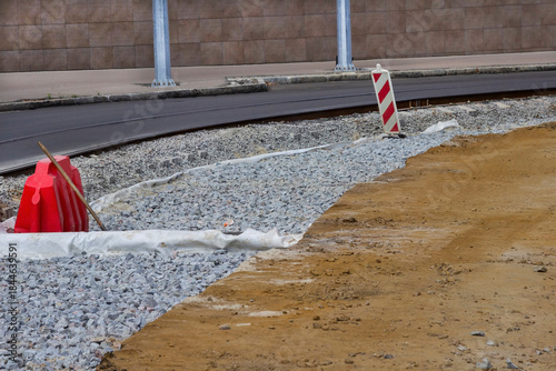 Tram line and road repairs. Gravel and soil on the road. Roadside warning signs.