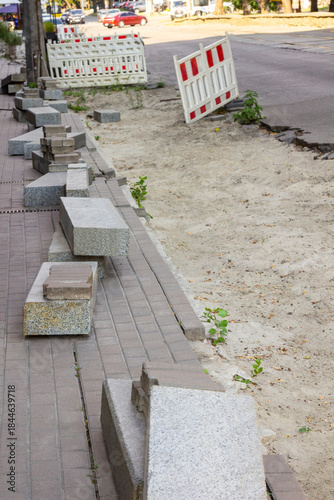 Curbstone on the road. Sidewalk repair. Warning signs.