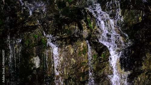 In a natural waterfall, water cascading down the rocks.
