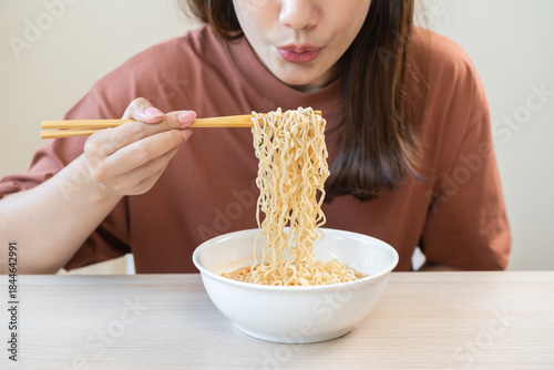Happy temptation, attractive asian young student woman, cute girl using chopsticks eating instant ramen, noodles soup from a bowl, cooking meal fast food lifestyle of traditional japanese person.