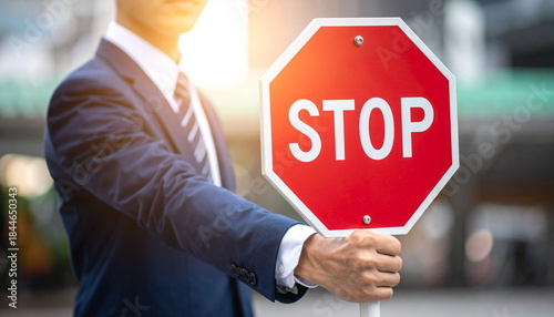 Businessman Holding a Red Stop Sign as a Gesture of Warning or Prohibition