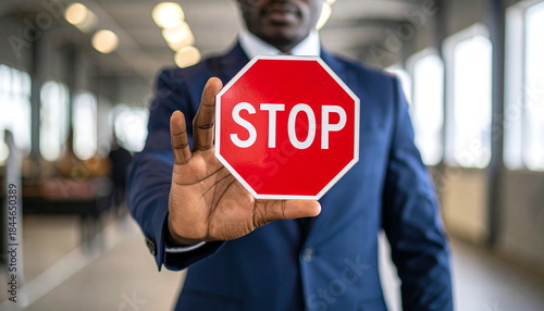 Businessman Holding a Red Stop Sign as a Gesture of Warning or Prohibition