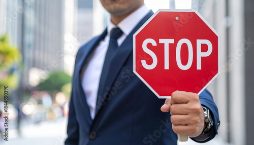 Businessman Holding a Red Stop Sign as a Gesture of Warning or Prohibition