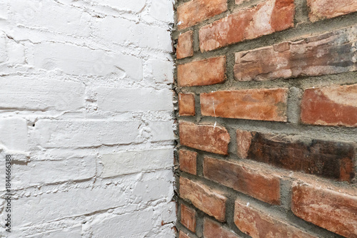 Corner of interior wall with contrast between white painted bricks and bare red brick masonry, construction background showing renovation, loft style design and modern industrial interior texture 