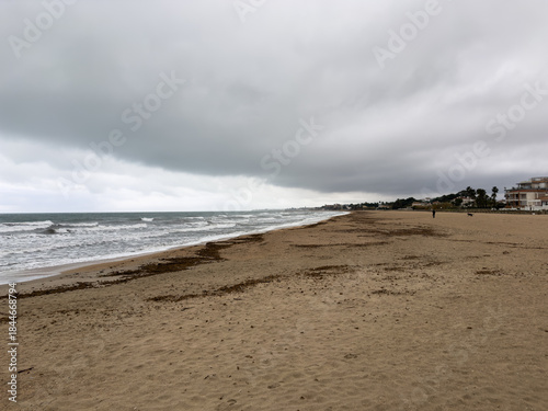 Stormy Mediterranean coastline with wide sandy beach and dramatic clouds in Oliva Spain