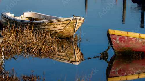 old fishing boats reflect in the harbours low water at Pin Mill Suffolk