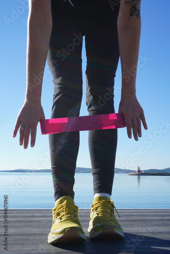 Outdoor resistance band workout showing woman preparing for exercise, fitness band, simple daily fitness routine, winter wellness, active lifestyle, strength training by the sea