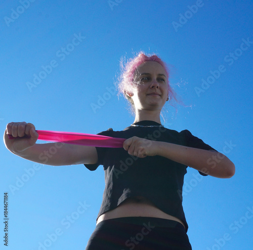 Morning outdoor fitness routine, woman training with resistance band in fresh air, simple daily exercise, active lifestyle, balance, wellness, self-care, and healthy habits.