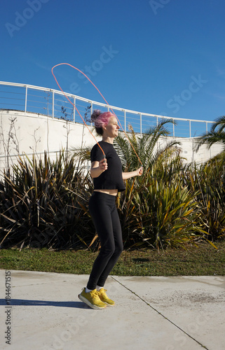 A woman skipping rope outdoors on a sunny winter day, practicing simple everyday fitness, healthy lifestyle. Casual Sportswear, jumping rope. Tropics winter