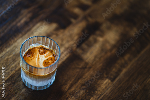 Dirty coffee, hot coffee with cold milk on wooden table at coffee shop. Top view and copy space concept.