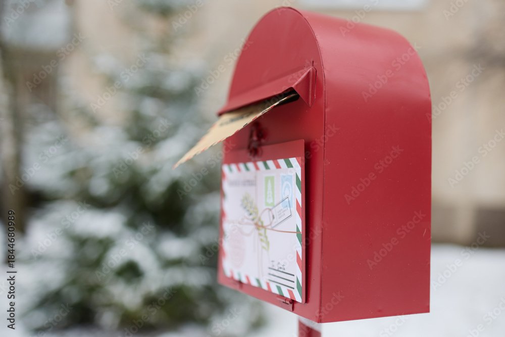 Obraz premium Santa's Mailbox. Red mailbox in snowy landscape holding a letter to Santa.