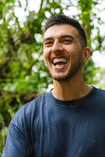 Close-up of a young happy man smiling outdoors in a natural green environment