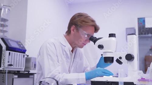 Scientist observes samples under microscope in laboratory