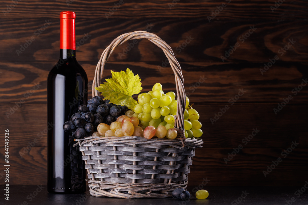 Obraz premium Wine bottle and basket of fresh grapes