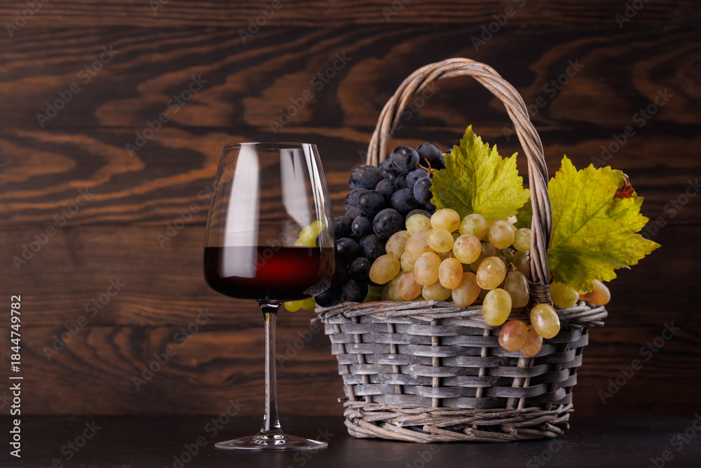 Obraz premium Red wine glass and basket of fresh grapes