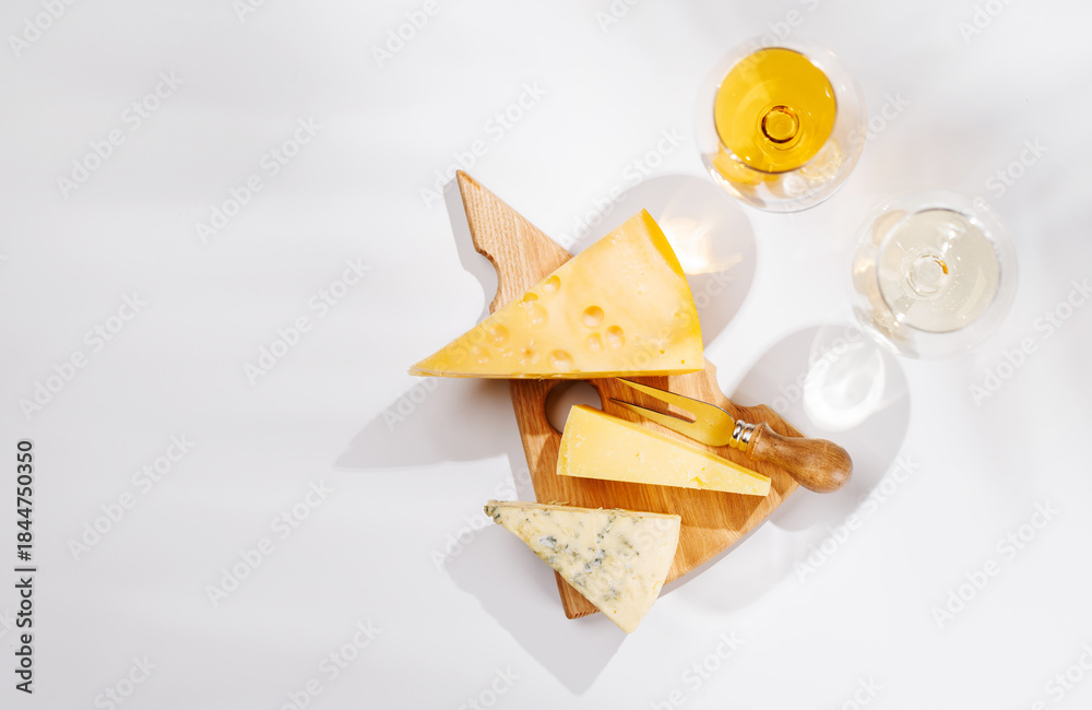 Obraz premium Assorted cheeses and wine glasses on white background