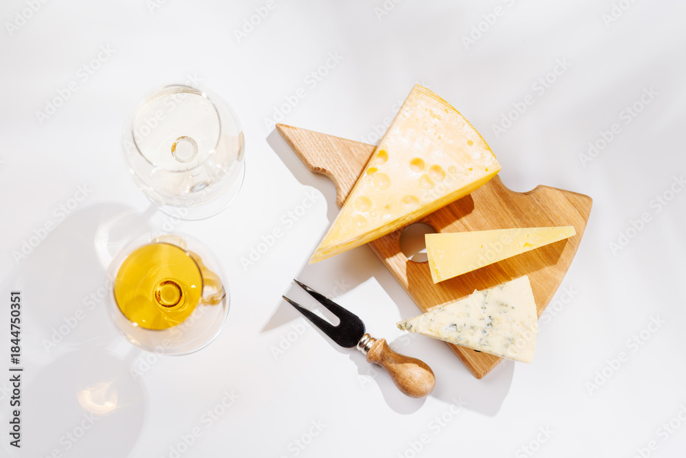 Obraz premium Assorted cheeses and wine glasses on white background