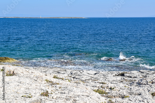 Fototapeta Naklejka Na Ścianę i Meble -  Rocky white cliffs and clear blue sea at Cape Kamenjak in Istria. Small island Fenera in background 