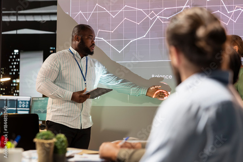 Foto Black business advisor presents capital funds and revenue data on annual reports in conference room, reviewing profit increase and budget allocation for new project