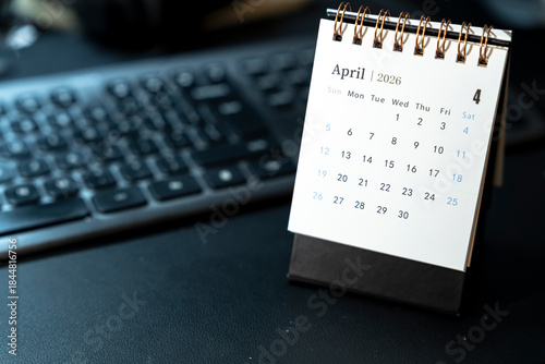 Foto A desk calendar displaying April 2026 sits on a dark keyboard