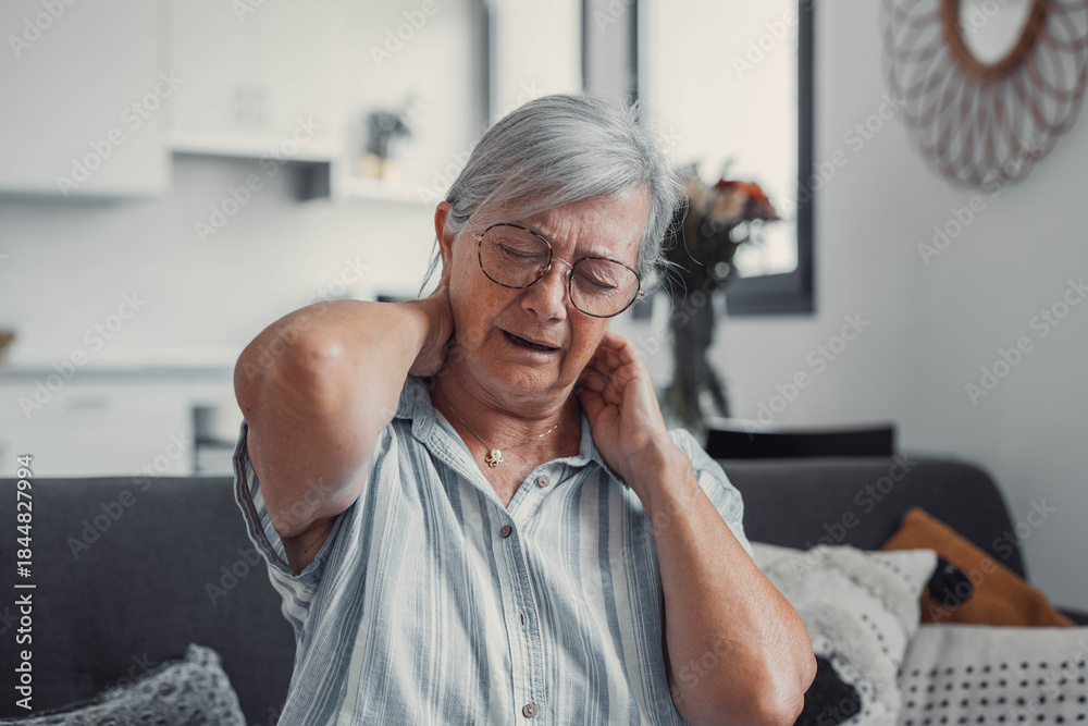 © Daniel - Senior woman sits on a sofa at home with neck pain and muscle discomfort. She appears tired and stressed, showing health challenges and fatigue during her daily life. © Daniel - Senior woman sits on a sofa at home with neck pain and muscle discomfort. She appears tired and stressed, showing health challenges and fatigue during her daily life.