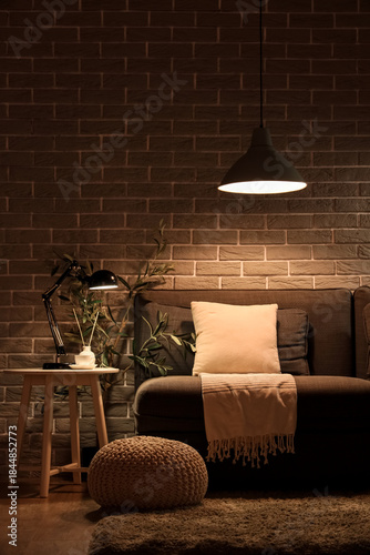 Tableau sur toile Stylish interior of living room with comfortable sofa, pouf and glowing lamps