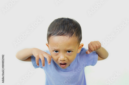 Portrait of a preschool-aged Asian boy expressing himself by imitating the pose of a lion about to pounce on its prey while roaring and shouting, raising his palms, isolated on a white background.
