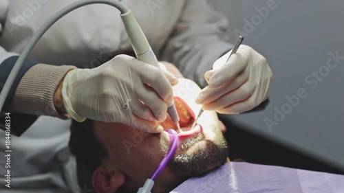 A dentist performs a professional teeth cleaning on a young patient using various instruments.
