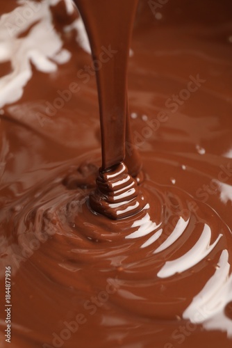 Tasty melted chocolate flowing down, closeup view